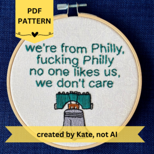 PDF pattern created by Kate, not AI. we're from Philly, fucking Philly, no one likes us, we don't care. Quote hand embroidered in eagles green. Silver, green, black liberty bell below. Displayed in light wooden hoop