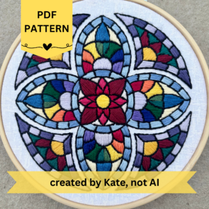 PDF Pattern created by Kate, not AI. Many colored hand embroidery based on traditional stained glass windows with flowers and rainbows in the design. Fabric is white on white cotton. Embroidery is displayed in light wood embroidery hoop.